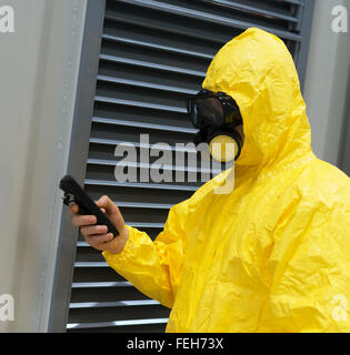 Worker in protective chemical suit checking radiation with geiger counter. Stock Photo