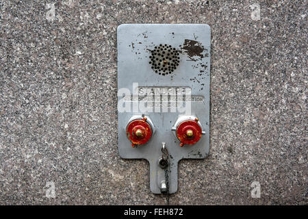 Metal fire department standpipe connections with red covers on granite wall facia Stock Photo