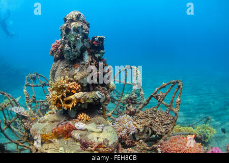 Buddha statue on the sea sand bottom on background of snorkeler swimming deep down into water to observe beautiful tropical reef Stock Photo