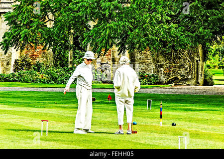 Two elderly ladies playing croquet on the lawns in front of the Bishops Palace in Wells, Somerset Stock Photo
