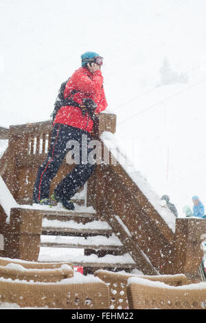 Man on his mobile phone in falling snow on ski holiday in ski resort of Courchevel, France, Europe Stock Photo