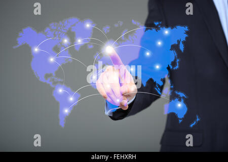 businessman touching a world map on the screen showing global connection between different continents. Stock Photo