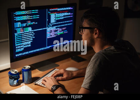 Thoughtful young programmer coding on computer in the evening at home Stock Photo