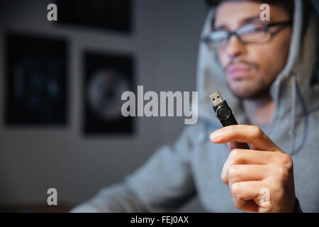 Handsome young man in glasses sitting in the room and holding usb cable Stock Photo