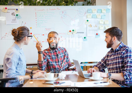 Multiethnic group of young people sitting in conference room and brainstorming on business meeting Stock Photo