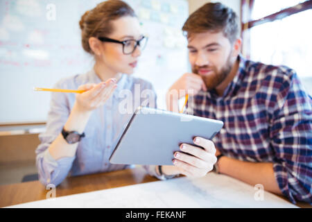 Two business people working with tablet computer in office. Focus on tablet computer Stock Photo
