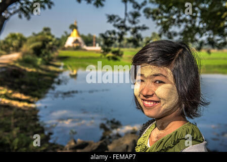 Portrait of a young burmese girl near a buddhist Stupa with thanaka on her face Stock Photo