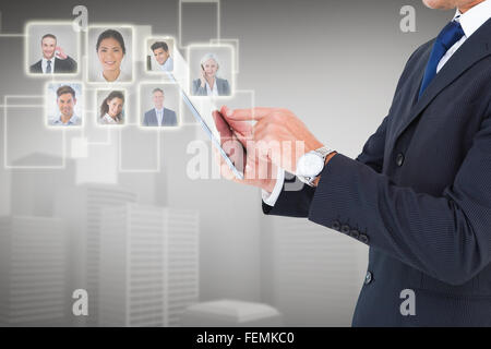 Composite image of businessman in suit using digital tablet Stock Photo