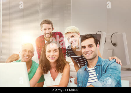 Composite image of creative business team using laptop in meeting Stock Photo