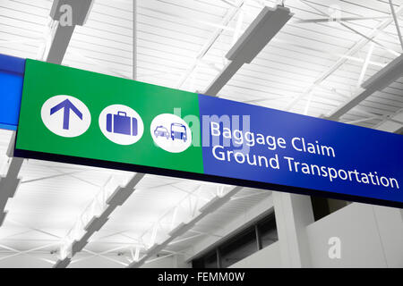 Airport baggage claim and ground transportation sign with suitcase, bus, and taxi symbols. Sign is blue and green. Stock Photo