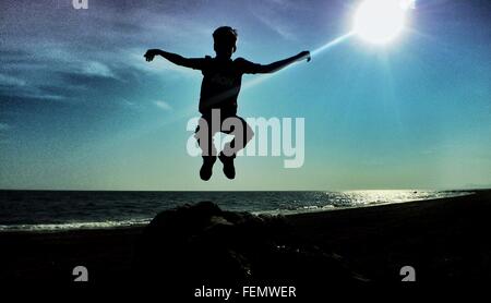 Boy Jumping Into Air Against Sun