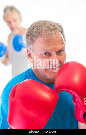 Senior man posing in a boxing stance wearing gloves Stock Photo