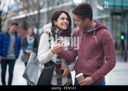 Young couple standing together in the city, looking at a smart phone Stock Photo