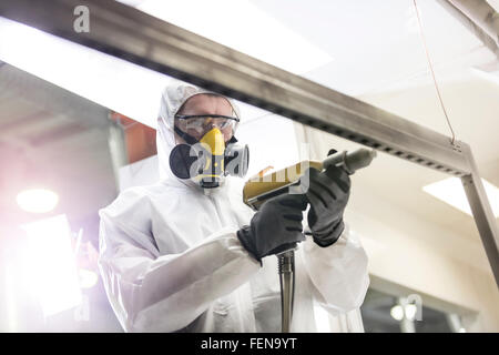 Worker in protective workwear using drill in factory Stock Photo