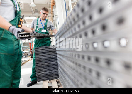 Workers lifting steel parts in factory Stock Photo
