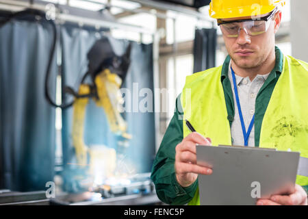 Worker in protective workwear with clipboard in factory Stock Photo