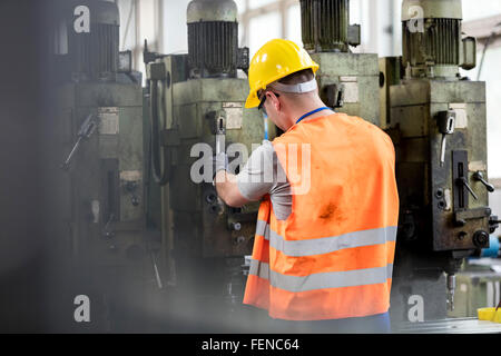 Worker in protective workwear operating machinery in factory Stock Photo