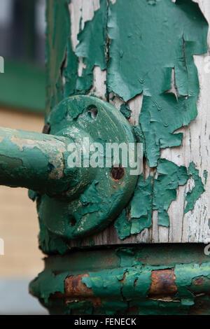 Old peeling green paint is seen on porch railings and posts of an old building Stock Photo