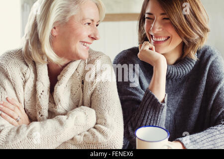 Laughing mother and daughter in sweaters drinking coffee Stock Photo