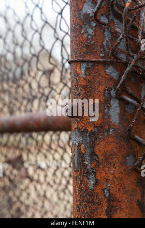 An old chain link fence and post is decaying and rusted out Stock Photo