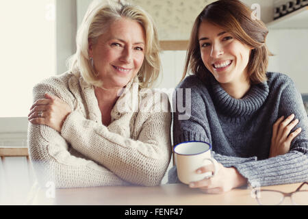 Portrait smiling mother and daughter in sweaters drinking coffee in kitchen Stock Photo