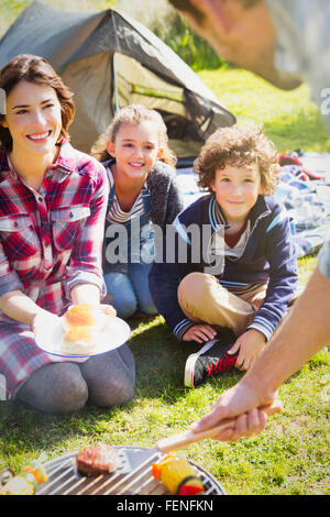 Family watching father barbecuing at campsite grill Stock Photo