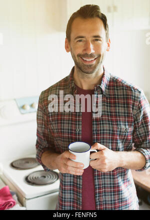 Portrait smiling brunette man drinking coffee in kitchen Stock Photo