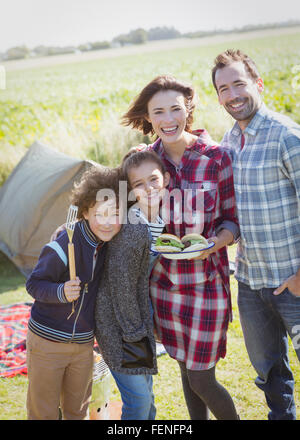 Portrait smiling family with barbecued hamburgers at sunny campsite Stock Photo