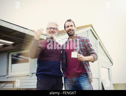 Father and son talking and drinking coffee outside house Stock Photo