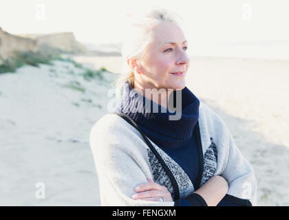 Pensive senior woman looking away on beach Stock Photo