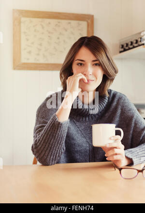 Portrait confident brunette woman drinking coffee at table Stock Photo