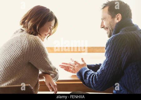 Laughing couple in sweaters at table Stock Photo