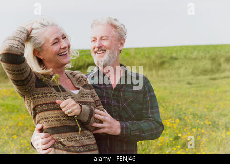 Smiling senior couple hugging in field Stock Photo