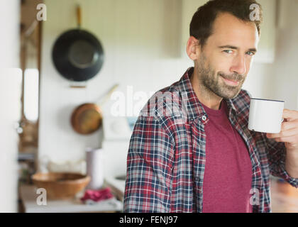 Portrait smiling brunette man drinking coffee in kitchen Stock Photo