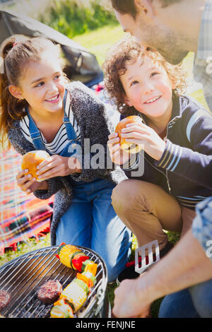 Father and kids eating hamburgers at barbecue grill Stock Photo