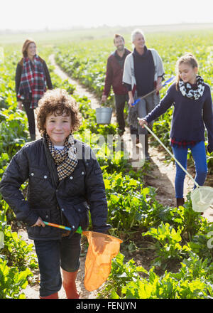 Portrait smiling boy with net walking in vegetable garden with family Stock Photo