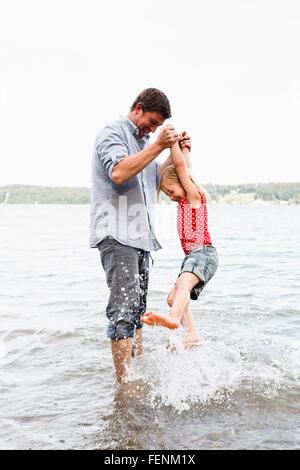 Mature man lifting up daughter from lake Starnberg, Bavaria, Germany Stock Photo