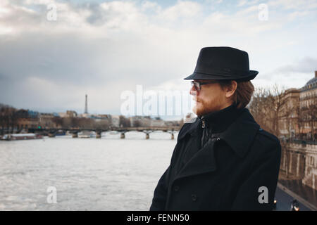 Serious Pensive Bearded Man Wearing Hat in Paris, France, Walking near Seine River. Headshot Composition, Space for Text. Stock Photo