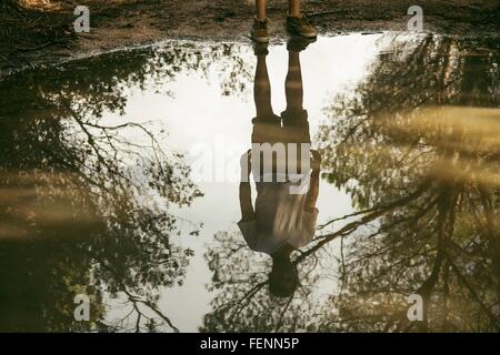 Full length reflection of young man in puddle, Costa Smeralda, Sardinia, Italy Stock Photo