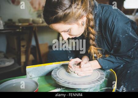 Young woman with plaited hair using pottery wheel Stock Photo