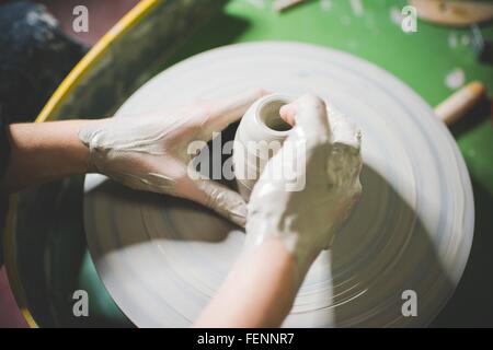 High angle view of young womans hands shaping clay on pottery wheel Stock Photo