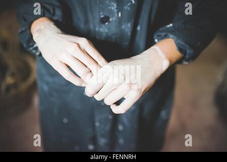 High angle cropped view of young womans clay covered hands Stock Photo