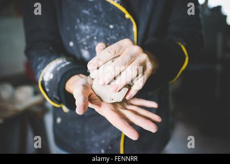 Cropped view of mid adult man squeezing clay in hands