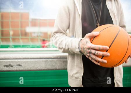 Mid adult man holding basketball, mid section Stock Photo