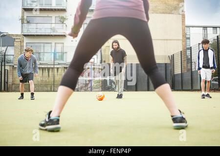 Group of adults playing football on urban football pitch Stock Photo