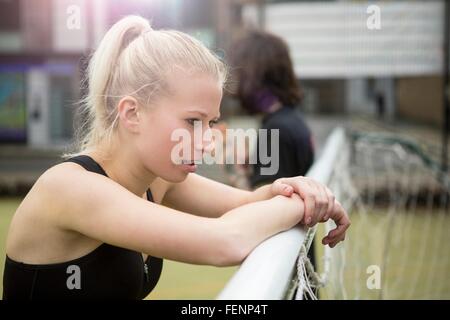 Young woman taking a break, leaning on football goal Stock Photo