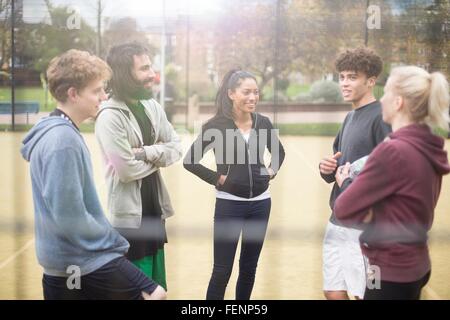 Group of adults standing on urban sports pitch, talking Stock Photo