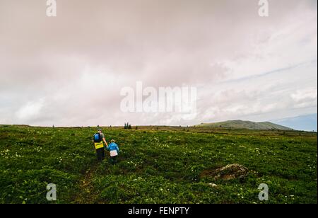 Rear view of father and daughter hiking in landscape, Ural Mountains, Russia Stock Photo