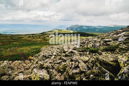 Rear view of woman hiking alone in rugged landscape, Ural Mountains, Russia Stock Photo