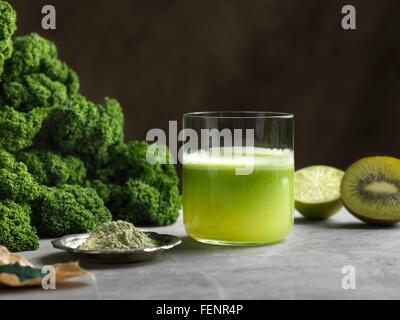 Green raw juice with halved kiwi and kale Stock Photo